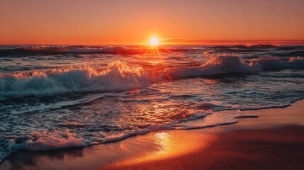 A vibrant orange sunset reflects on ocean waves as they crash onto a sandy beach