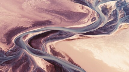 Aerial view captures winding, turquoise rivers carved through a textured, pinkish-beige landscape