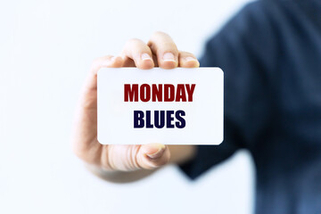 Monday blues text on white blank card holding by hand isolated on white background
