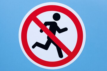 A white sign with a red circle  line over a running black figure on a light blue background