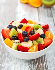 Fresh fruit salad in a white bowl on a rustic wooden table
