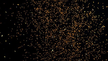 Golden confetti floating in midair against a dark backdrop, capturing a festive and lively moment.