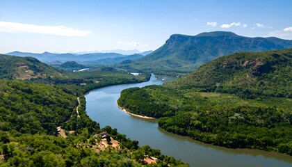 Panoramic view of a winding river flowing through lush green valleys and hills under a clear blue sky