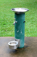 Fototapeta premium Green public water drinking fountain with a dog pet bowl in a park