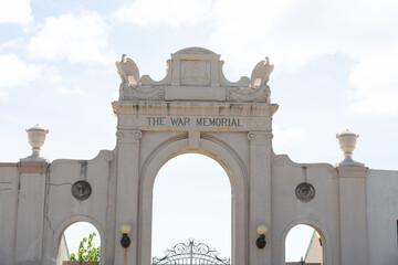 Obraz premium Architectural war memorial archway with eagles. The monument's classical style is set against a sunny, cloud-strewn sky, evoking remembrance.