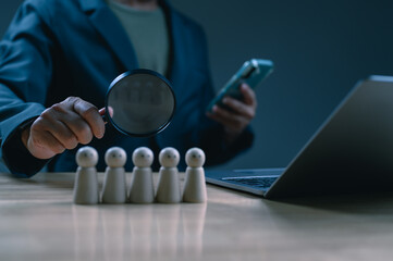 Businessperson diligently holds magnifying glass, examining wooden figures. Expert identifies ideal...