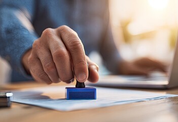 Close-up of a hand stamping a document.  A person stamps a business document with a blue stamp