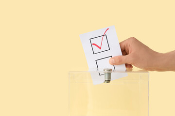 Voting man near ballot box on yellow background