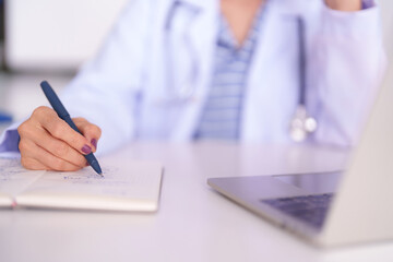 Fototapeta premium Adult Asian doctor hand writing notes in notebook at medical office desk healthcare professional working diligently on research studies