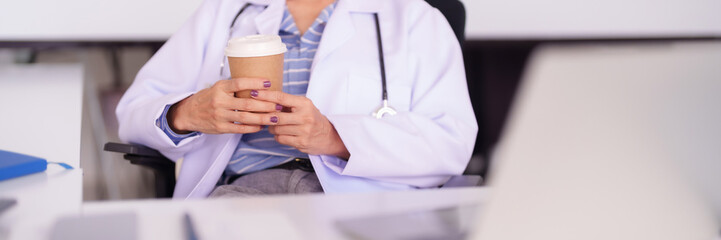 Asian Adult Female Doctor Holding Coffee Cup Relaxing in Office Medical Setting Healthcare Professional Taking a Wellness Break