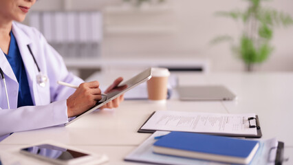Fototapeta premium Asian adult doctor uses digital tablet for patient care modern medical office technology integration professional healthcare