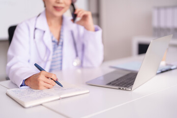 Asian Adult Doctor Writes Patient Notes On Call Medical Office Professional Uses Laptop For Healthcare Management Consulting