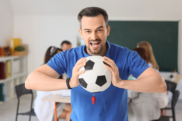 Male PE teacher with soccer ball in school office