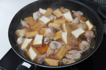 鶏もも肉と厚揚げの煮物を作る様子
