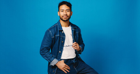 Blue background, fashion and portrait of man with glasses for prescription lens, vision and...