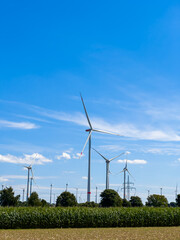 This scenic landscape shows modern wind turbines in blue skies, blending nature and renewable energy, highlighting farmland and fields while showcasing engineering and environmental significance