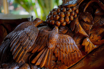 Intricate Wooden Carving of Birds and Grapes with Natural Backdrop