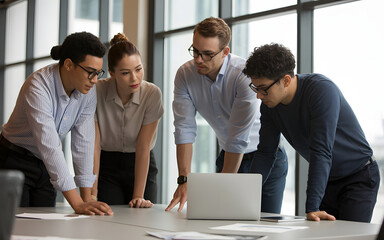 Group of diverse professionals collaborating around a laptop in a modern office space setting
