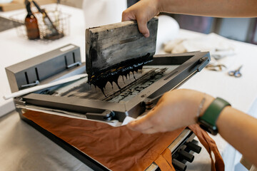 Manual Silk Screen Printing on Fabric – Close-up of Hands Working with Screen Printing Machine in Workshop
