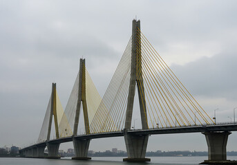 Obraz premium A modern cable-stayed bridge with yellow cables and concrete towers on a calm, gray day.