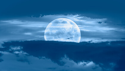 Night sky with full moon in the dark clouds and darkblue sea in the foreground 