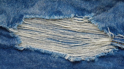 Close-up of Distressed Denim with Ripped Fibers Revealing Texture and Wear