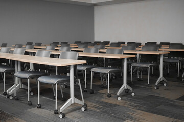 Long rows of desks with chairs inside a dark, empty university lecture hall