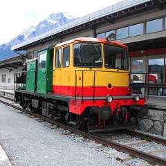 Obraz premium Kolorowy pociąg spalinowy na stacji górskiej