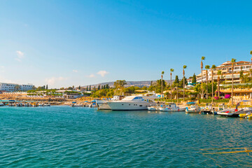The marina in Paphos, Cyprus, shines under the bright Mediterranean sun — a picturesque spot with docked boats, seaside cafés, and palm-lined promenades, perfect for a relaxing coastal stroll.