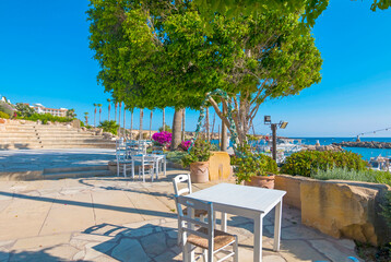 Traditional Greek restaurant in Paphos, Cyprus — whitewashed walls, blue accents, and blooming flowers set the scene for delicious local cuisine in a charming Mediterranean atmosphere.