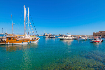 The marina in Paphos, Cyprus, shines under the bright Mediterranean sun — a picturesque spot with docked boats, seaside cafés, and palm-lined promenades, perfect for a relaxing coastal stroll.