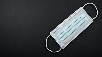 A white face mask placed on the lower right side on a black background.