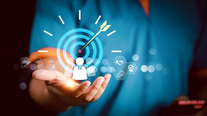 Businessman hand holding digital target with dart and customer icon, symbolizing business goal, marketing strategy, customer focus, leadership and corporate success.