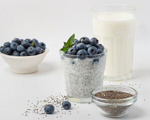 Glass with chia pudding, fresh blueberries, kefir, milk, chia seeds and a bowl with berries. Healthy eating concept, superfood.