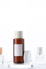 Cosmetic bottle with a white cap beside soft cotton pads on the bath shelf with perfumes , luxury skincare toner or essence, perfect for cleansing and gentle facial treatments.
