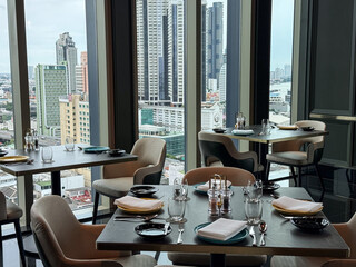 Bangkok, Thailand - June 30, 2025: Rooftop fine dining restaurant with panoramic city view and elegantly set tables in luxury atmosphere © Bankerok