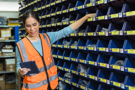 Happy woman worker engineer technician staff work in factory products inventory parts storage room