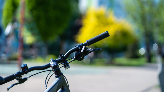 Bicycle handlebars in urban park on sunny day - Powered by Adobe