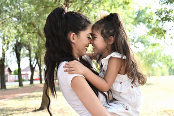 Happy girl kid hugging mom in the nature