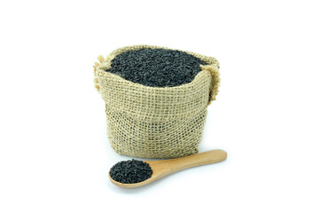 Black sesame seeds in bag sack and a wooden spoon isolated on white background close up stack, oily seeds, healthy food