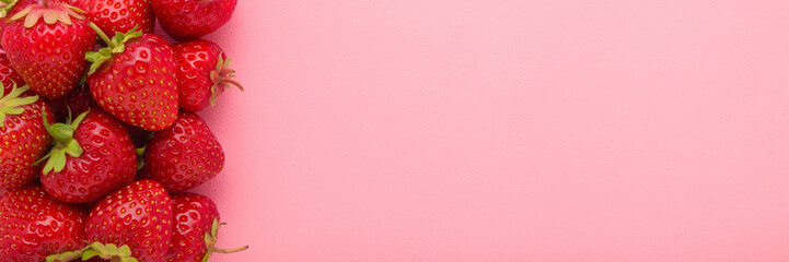 Red bright strawberries on light pink table background. Pastel color. Fresh berries. Closeup. Wide banner. Empty place for text. Top down view.