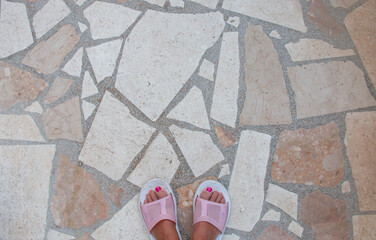 Top view of feet with red nails standing on marble floor capturing a serene summer moment.