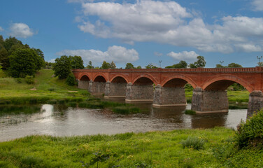Latvia, City of Kuldiga - the ancient bridge crosses the Vetna River, a few meters from the waterfalls. The calling card of the city.