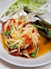 A plate of spicy Thai papaya salad with shrimp and stir-fried vegetables is a delicious and healthy appetizer