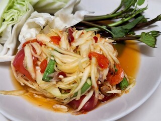 A plate of spicy Thai papaya salad with shrimp and stir-fried vegetables is a delicious and healthy appetizer