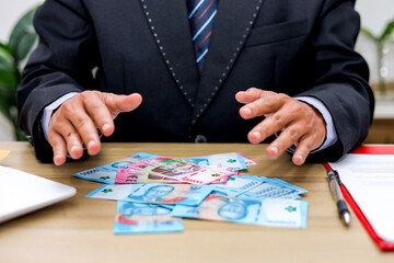 Businessman in a Suit Spreads out Indonesian Rupiah Banknotes Suggesting Illicit Dealings