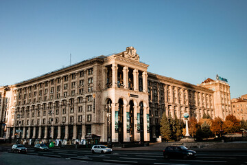 Fototapeta premium The iconic Main Post Office building on Maidan Nezalezhnosti in Kyiv, Ukraine, under a clear blue sky at sunset. The classic Stalinist-style architecture is bathed in warm, golden light.