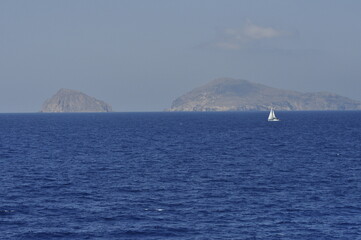 Fototapeta premium A Serene Ocean View Featuring Distant Islands and a Graceful Sailboat in the Distance