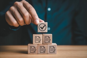 Hand placing check mark block atop rejected document blocks on wooden surface in soft focus
