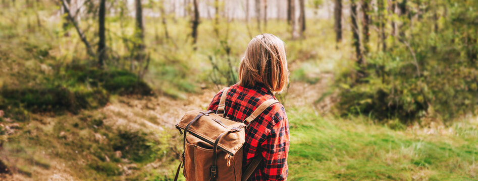 A girl in a red shirt and with a backpack is walking in the forest. Hiking in sunny autumn forest.